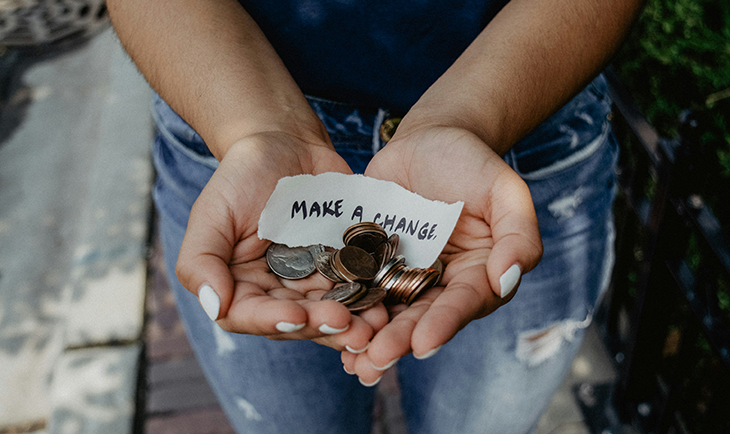 Woman holding coins with a sign that says Make a Change